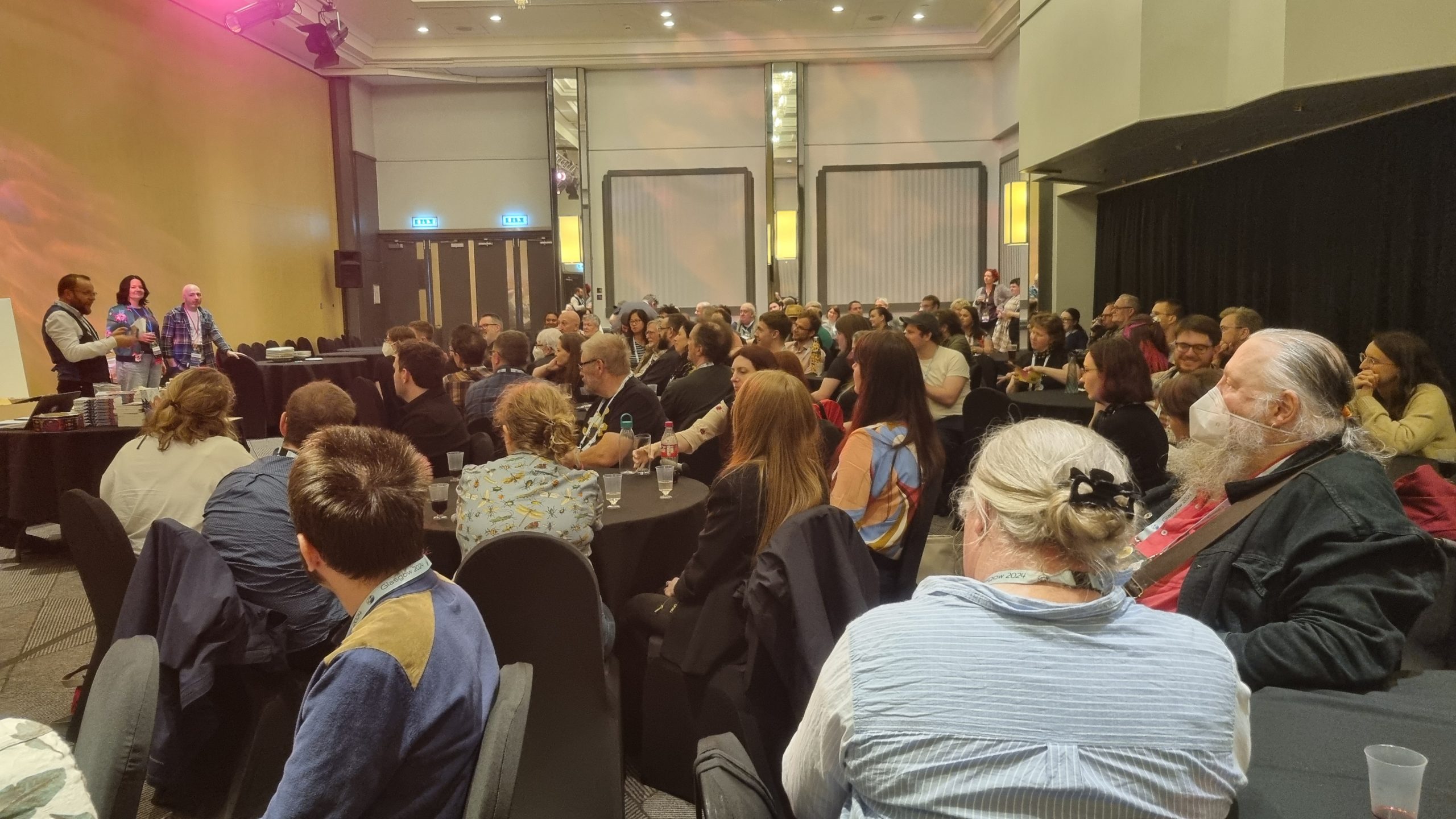 The room Argyll 3 at the Crowne Plaza, filled to capacity (probably a hundred people) while editors Brian M. Milton, E.M. Faulds and Neil Williamson, three caucasians, address the crowd.