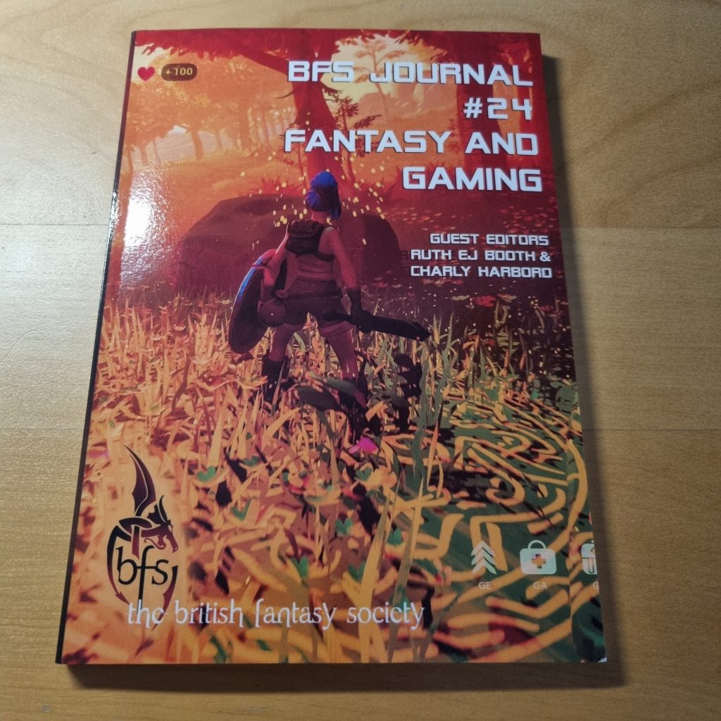 The cover of a BFS journal, featuring a fantasy character standing in a forest with UI features as you might expect from a videogame. Text reads: "BFS Journal #24: Fantasy and Gaming Guest Editors Ruth EJ Booth & Charly Harbord The British Fantasy Society"